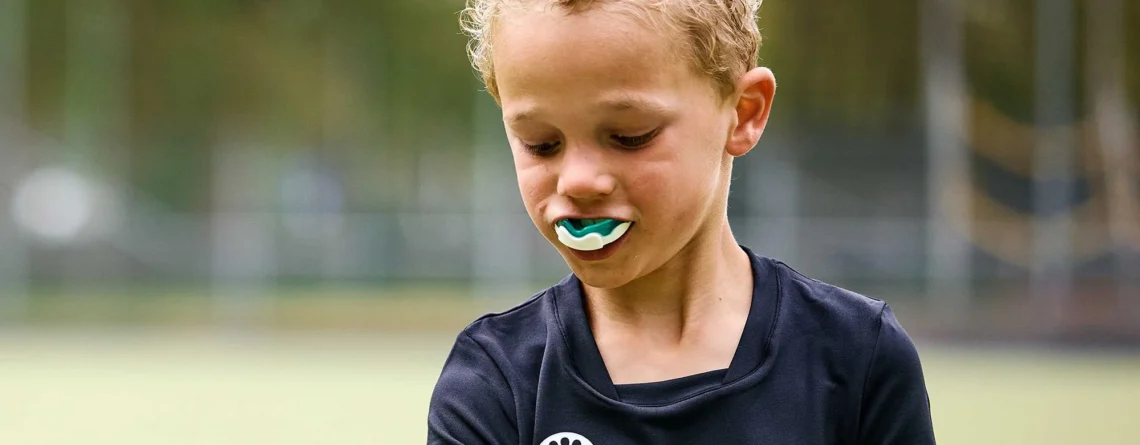 Child wearing a custom sports mouthguard to prevent sports-related dental injuries during summer activities
