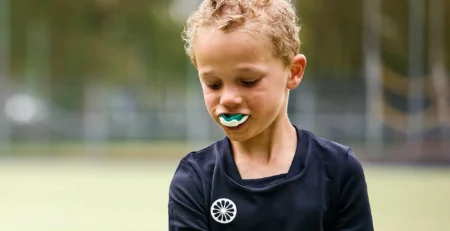 Child wearing a custom sports mouthguard to prevent sports-related dental injuries during summer activities