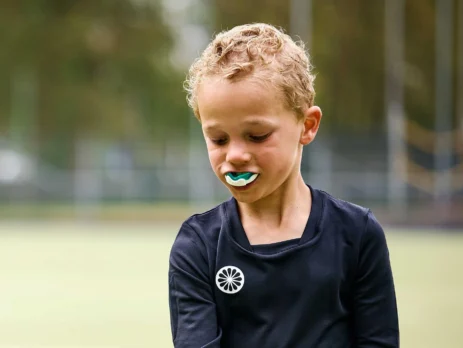 Child wearing a custom sports mouthguard to prevent sports-related dental injuries during summer activities